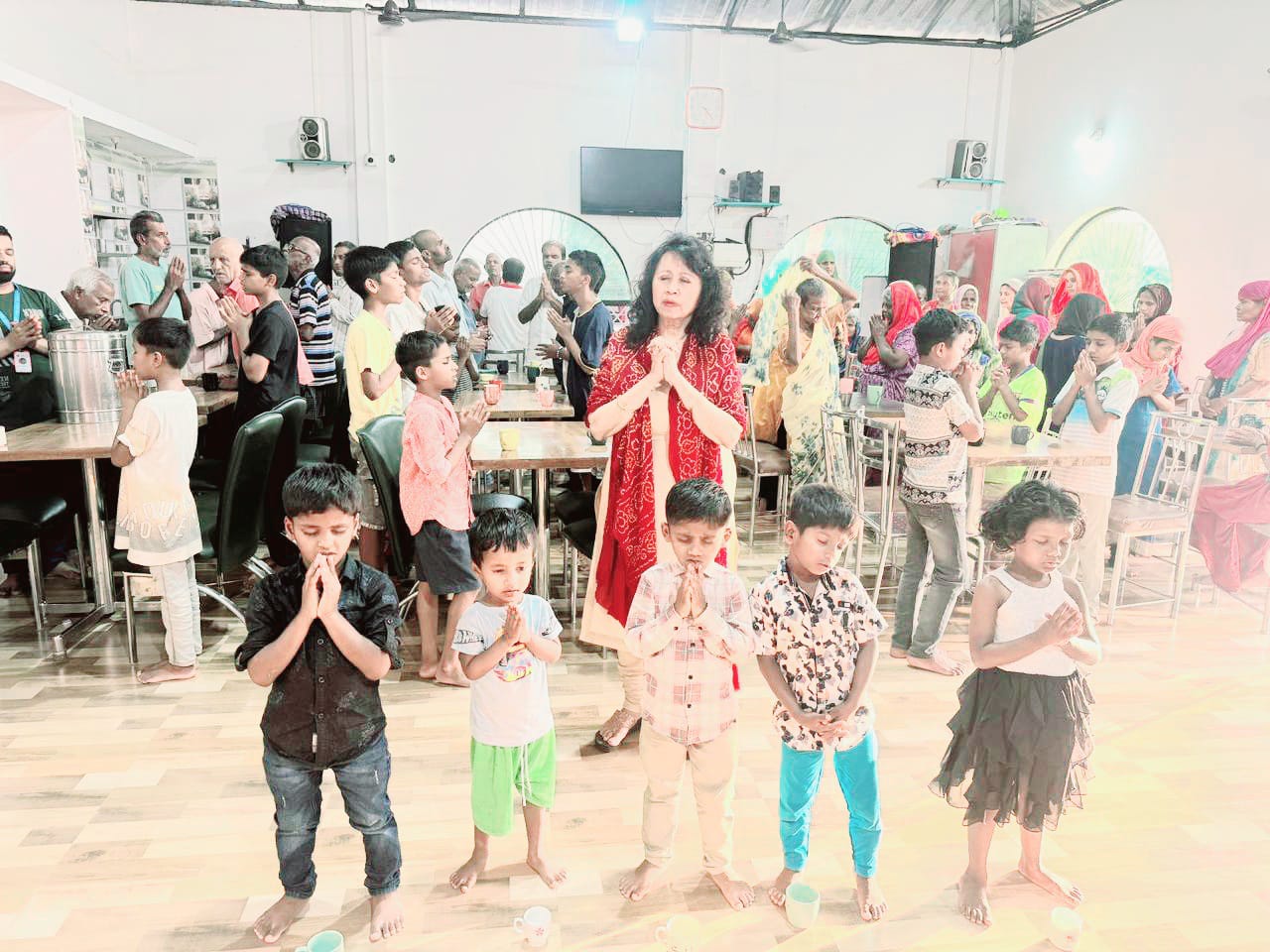 Kadambari in prayer with children and community members