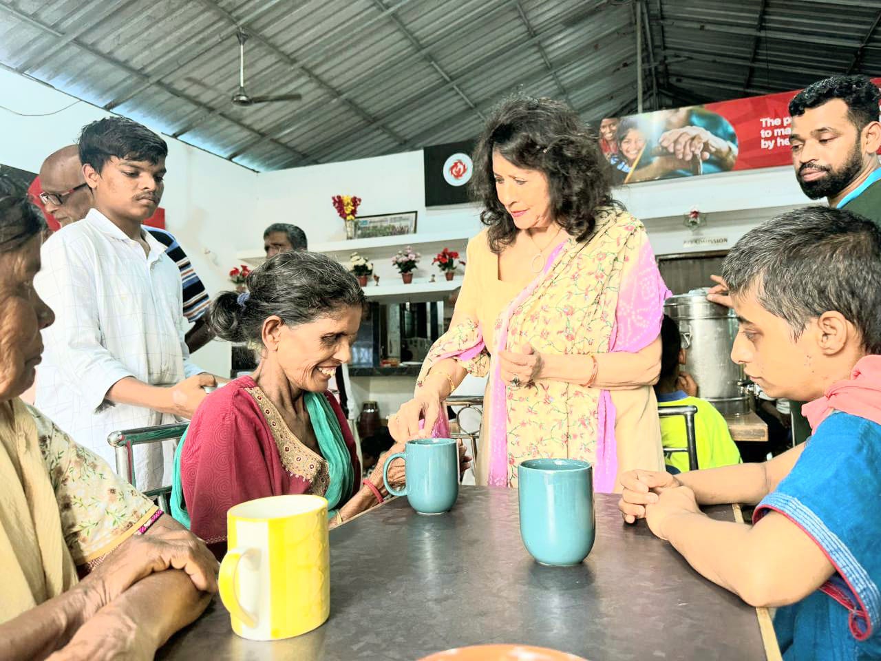 Kadambari serving tea to a community member